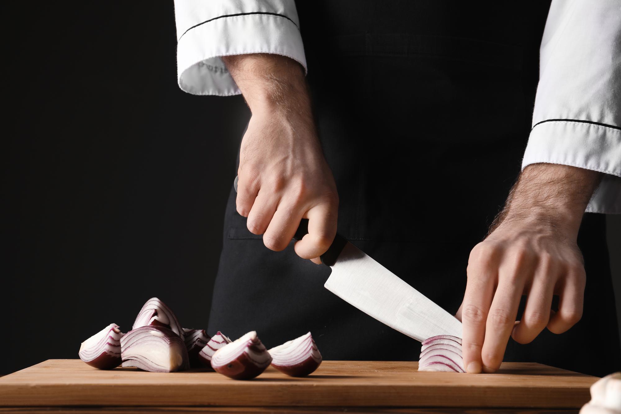 Chef demonstrando técnica de corte em bancada elegante